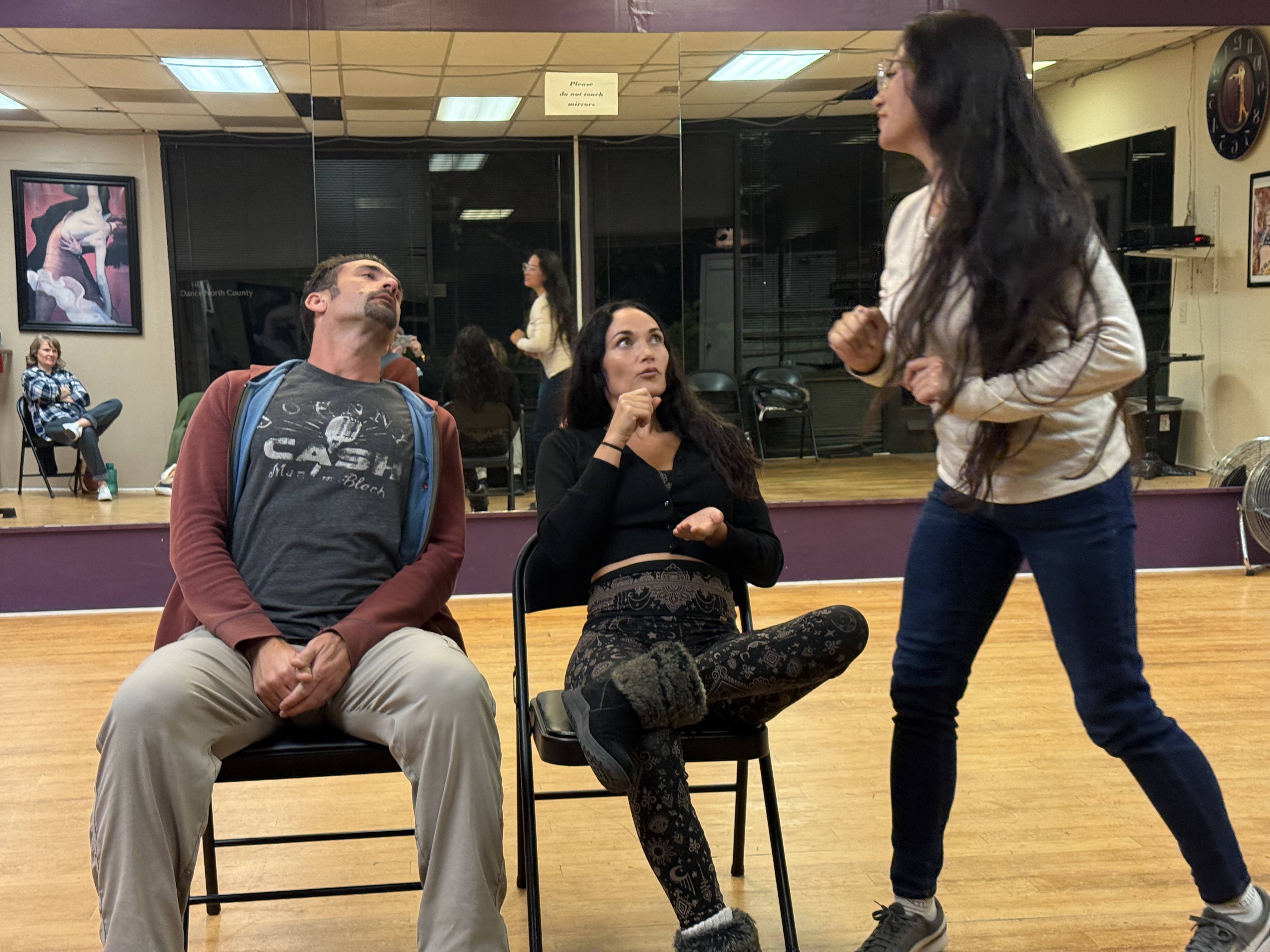Workshop participants mid-scene in an improv exercise at a dance studio
